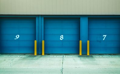 Three blue shutter doors numbered 9, 8, and 7 with yellow barriers in urban environment.